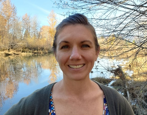Woman with brown hair and blue eyes smiles at camera.